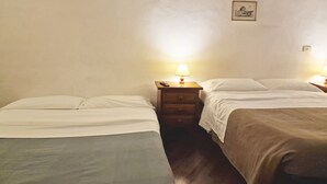 Une chambre simple avec deux lits, une table de chevet avec une lampe et un petit tableau encadré au mur.