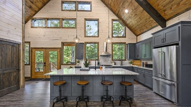 A spacious kitchen with a large island, bar stools, and a stainless steel refrigerator.