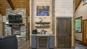 A cozy cabin interior with a stone fireplace, a flat-screen TV, and a wooden door.