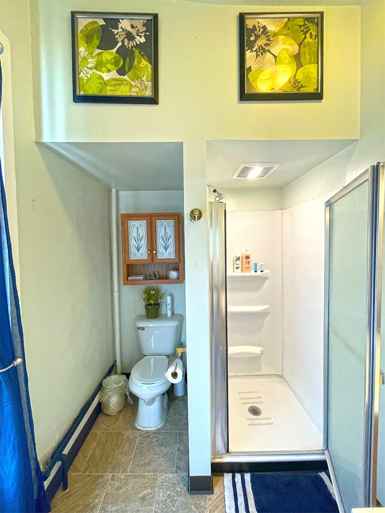 Un baño pequeño con inodoro, un mueble auxiliar y cabina de ducha.