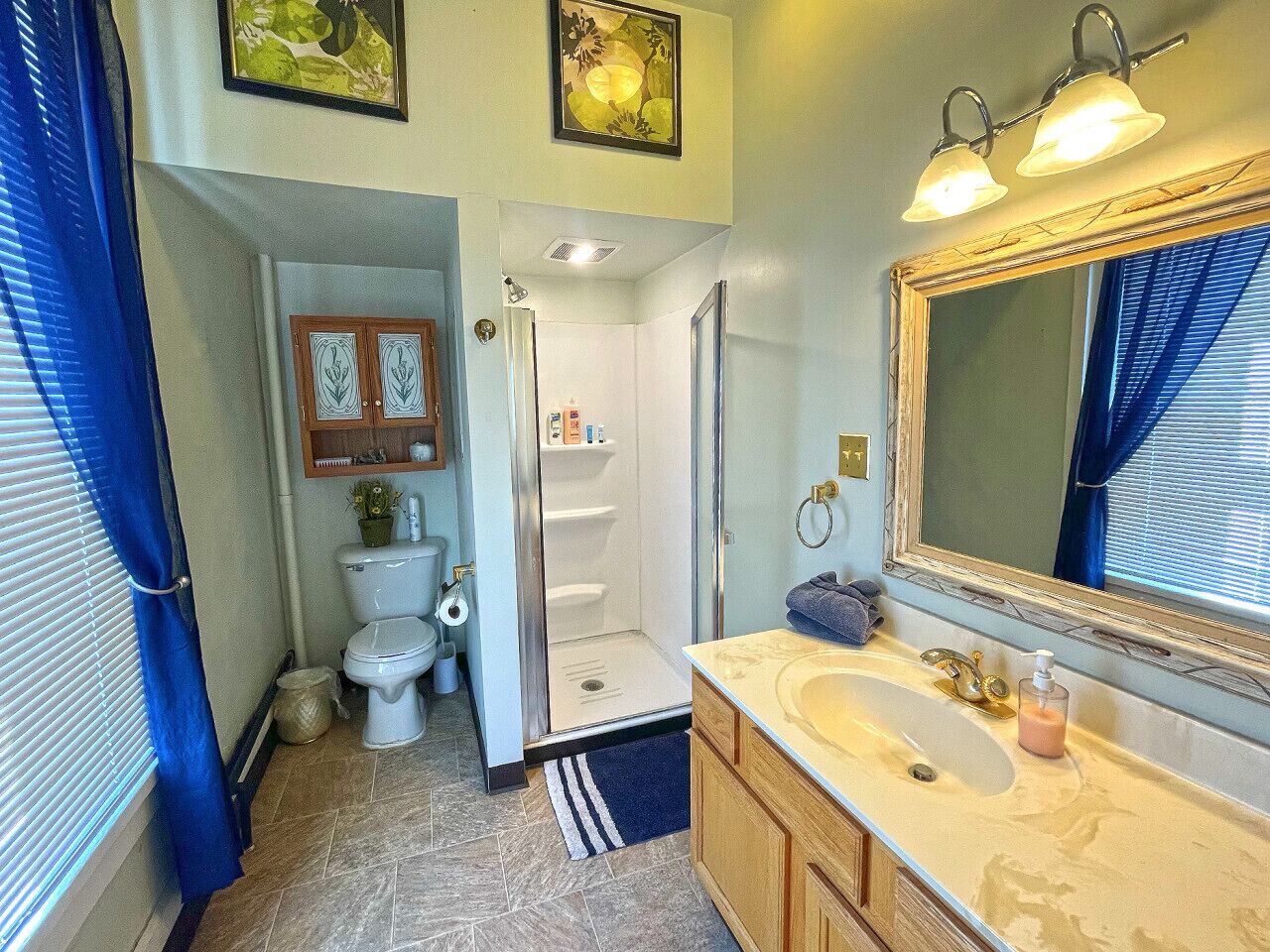 A bathroom with a shower, toilet, sink, and mirror.