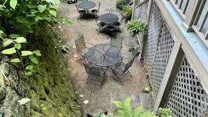 A courtyard with a brick building, a metal fence, and a table with chairs. - Nye's Place in Heart of Historic Roscoe Village (Coshocton)