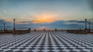 A checkered floor leading to a railing overlooking a body of water with a sunset in the background. - Studio nearby Hospital and Train railway. (Livorno)