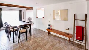 A spacious dining area with a long table and chairs, a bench with a lantern, and a red towel on a rack. - Never Lonesome Hunter: Smart 4bd Getaway near Mtn (Hunter)