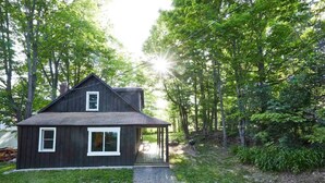 A rustic cabin with a porch, surrounded by dense forest. - Never Lonesome Hunter: Smart 4bd Getaway near Mtn (Hunter)