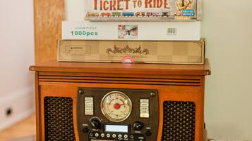 Une table en bois, sur laquelle on trouve une radio ancienne, une pile de livres et des magazines.