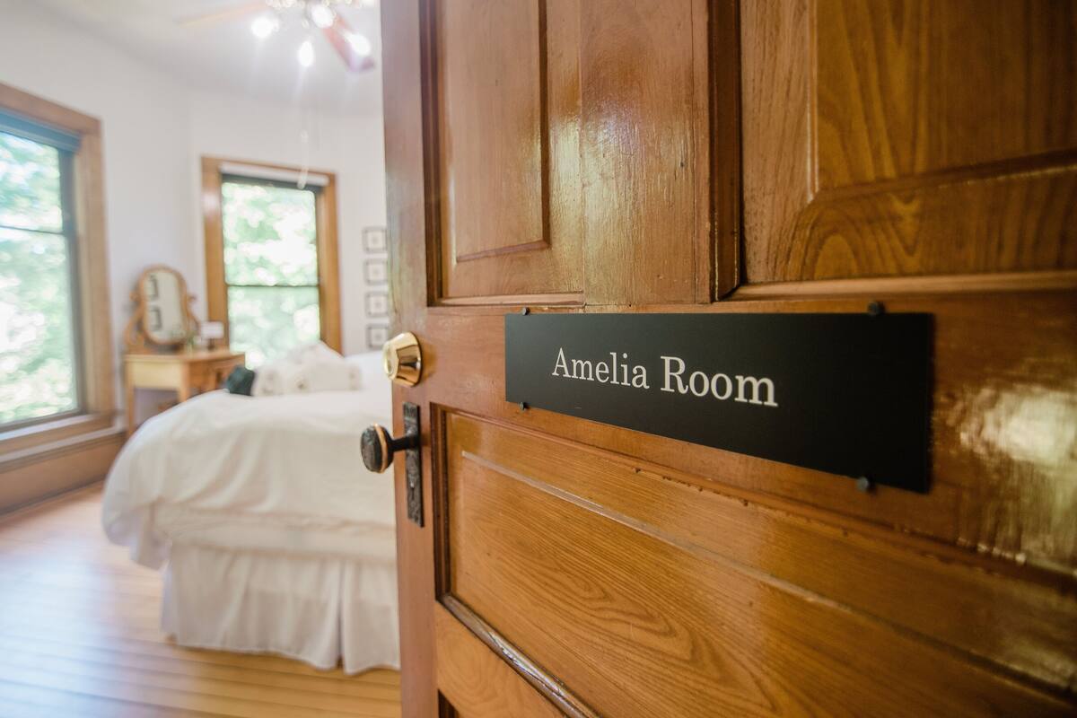 Une porte en bois sur laquelle est apposée une plaque indiquant : « Chambre d’Amélia ».
