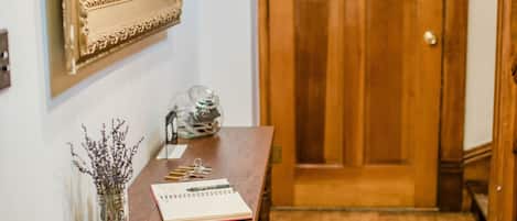 Een houten deur met een ruit, een spiegel met een sierlijk frame, en een houten tafel met een vaas en een bord eten.