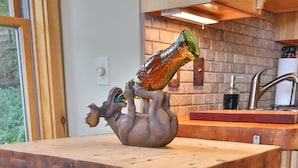 Une cuisine dotée d’un îlot central en bois, d’un évier en pierre rustique et d’une sculpture en forme de bouteille.