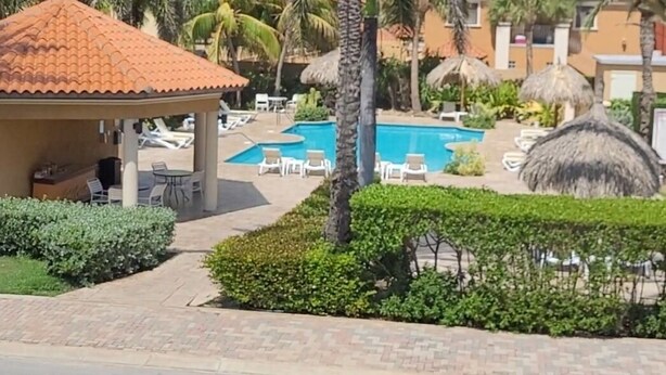 Un resort con piscina, palmeras y sillones de descanso.