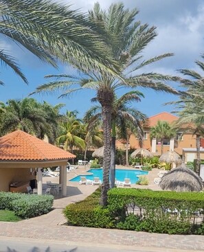 A resort with a swimming pool, palm trees, and lounge chairs.