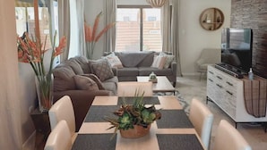 Una sala de estar moderna con comedor, que incluye un juego de sofá, una mesa de centro y un mueble para televisión.