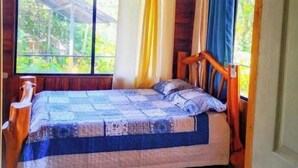 A single bed in a cabin with a wooden ceiling, large windows with curtains, and a view of greenery outside. - Terrazas del Golfo Oceanfront, Room Manigordo! Pet Friendly! (Provincia de Puntarenas)