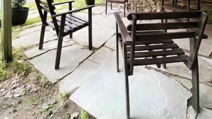 An outdoor patio with stone walls, string lights, and wooden furniture.