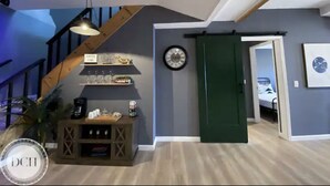 Um quarto amplo com escada de madeira, porta deslizante verde, relógio e pequena mesa com objetos.
