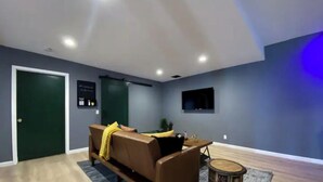 Uma sala de estar moderna com um sofá marrom, uma mesinha redonda e uma parede de destaque azul escura.