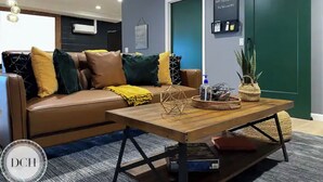 Uma sala de estar moderna com um sofá de couro marrom, uma mesa de centro de madeira e uma porta verde.