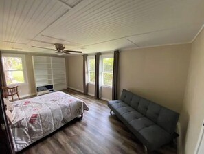 Relax in this serene space with a high ceiling, ceiling fan, and comfortable bed, surrounded by lush views.