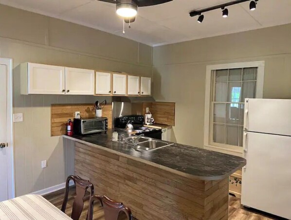 Kitchen features a central island with sink and stovetop, along with ample storage in the adjacent cabinets.