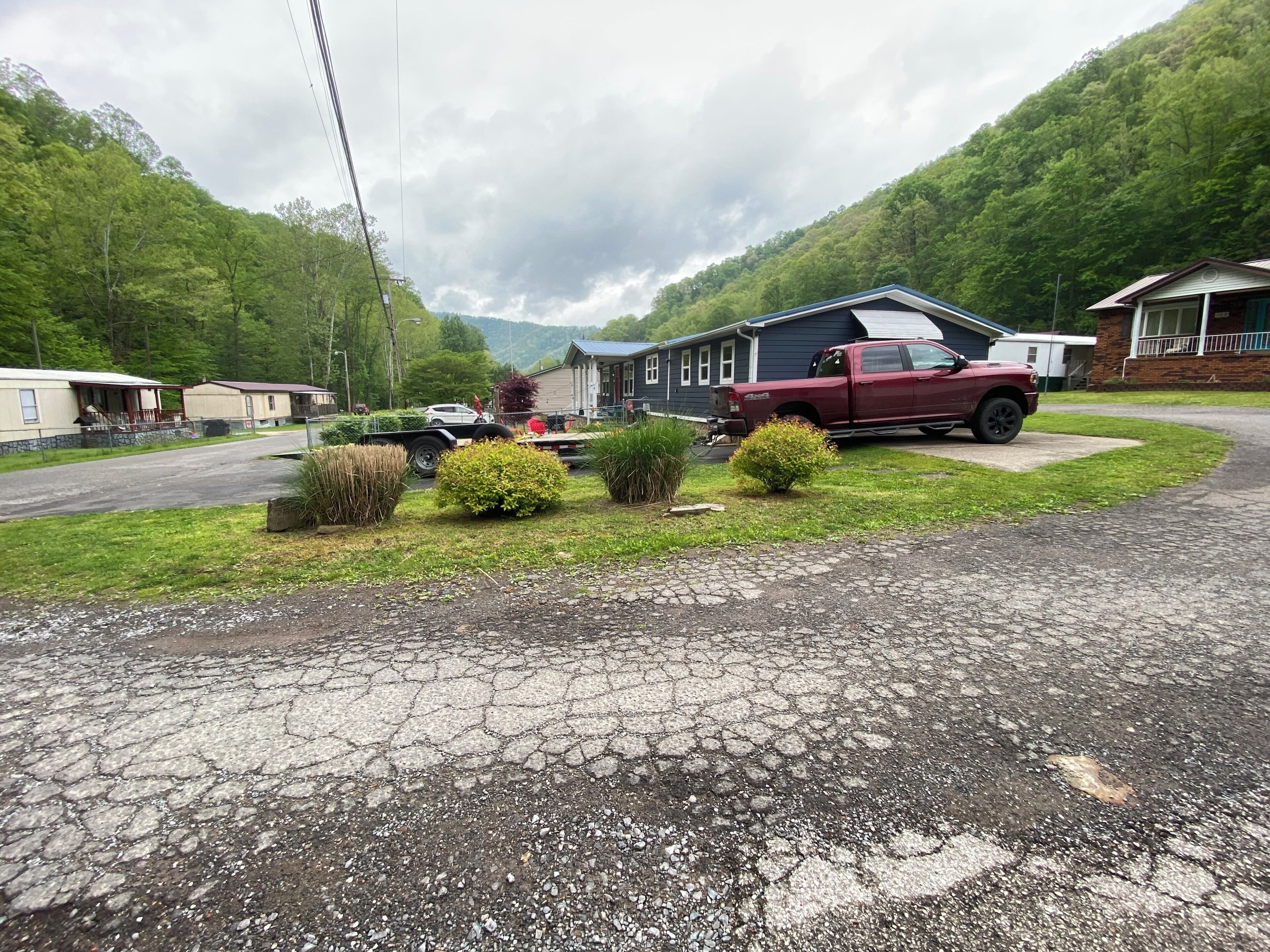 A residential area with a red truck parked in front of a house, a driveway, and a grassy area with bushes.