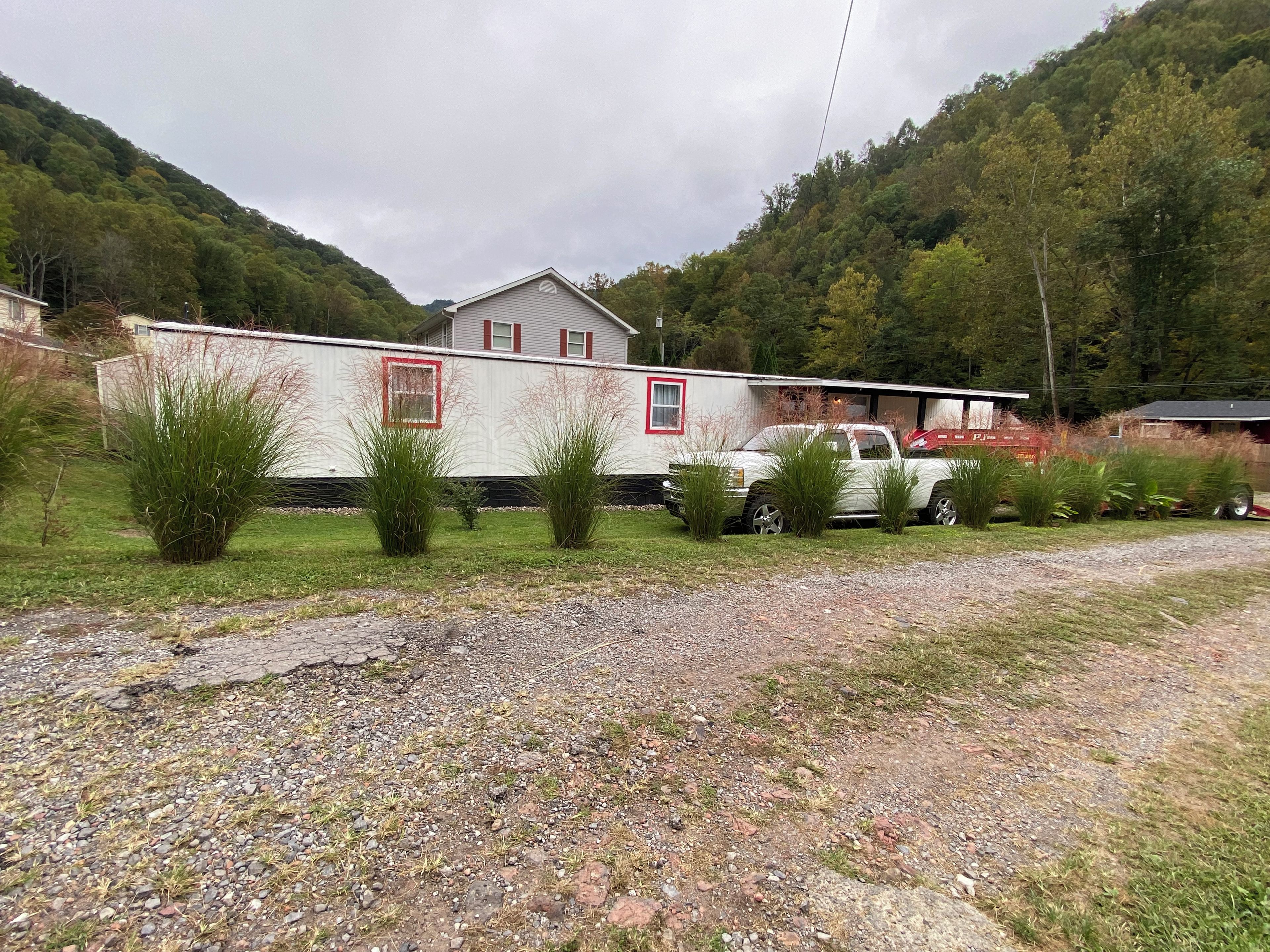 A mobile home with a gravel driveway and a truck parked in front.