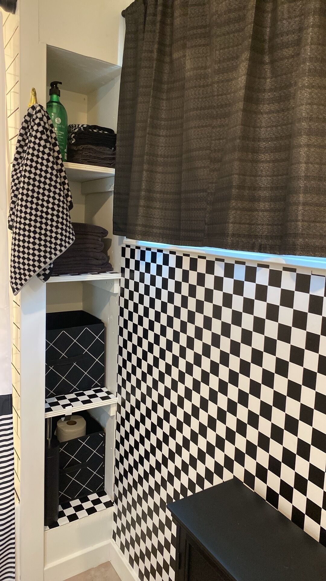 A bathroom with a checkered tile backsplash, a towel rack with a patterned towel, and a green bottle on a shelf.
