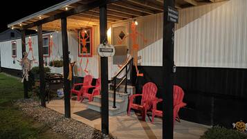 Un bâtiment doté d’un porche couvert, de chaises rouges et de décorations d’Halloween, notamment des squelettes.
