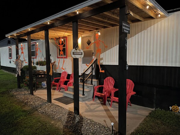 A building with a covered porch, red chairs, and Halloween decorations including skeletons.