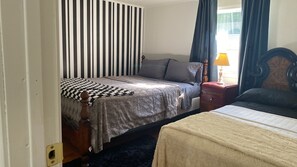 Et soveværelse med seng, natbord, lampe og gardiner.