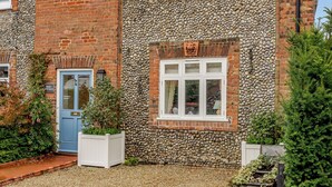 A brick building with a stone facade, a blue door, and a window with white frames. - 3 bedroom accommodation in Holt (Holt)
