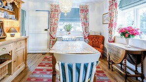 A dining area with a chandelier, patterned curtains, and a view of the outdoors. - 3 bedroom accommodation in Holt (Holt)