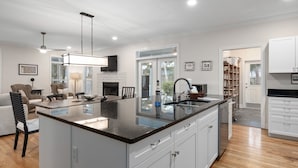 Una cocina moderna con una isla grande, muebles blancos y una chimenea.