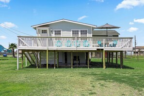 Ein zweistöckiges Haus mit überdachter Veranda und einer kleinen Terrasse.