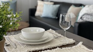 A dining table with a white placemat, a bowl, a wine glass, and cutlery. - Cute, Cozy and Clean cottage by the Sea! (Freeport)