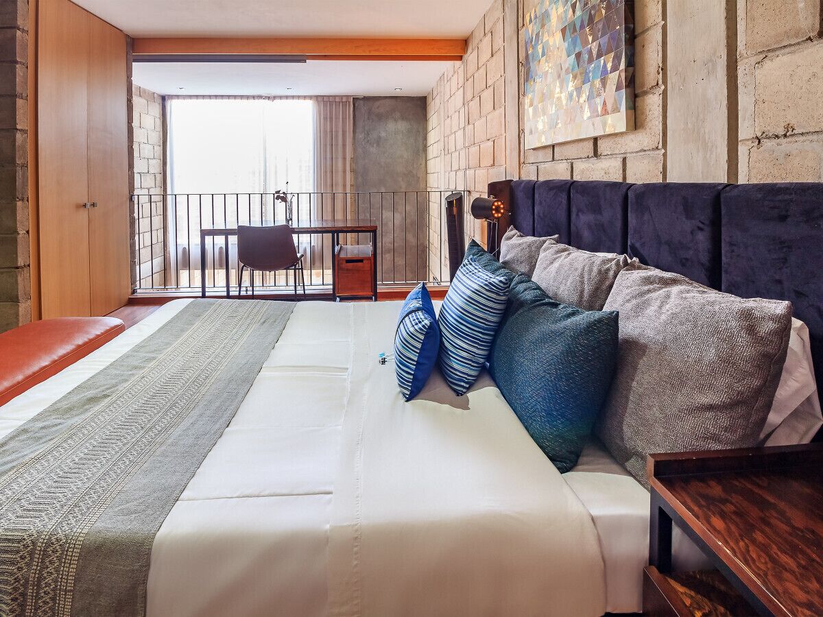 Un dormitorio con una cama grande, un escritorio y un balcón.