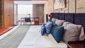 Une chambre avec un grand lit, un bureau et un balcon.