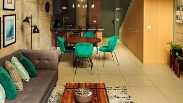 Una sala moderna con sofá, mesa de centro, comedor y escalera.