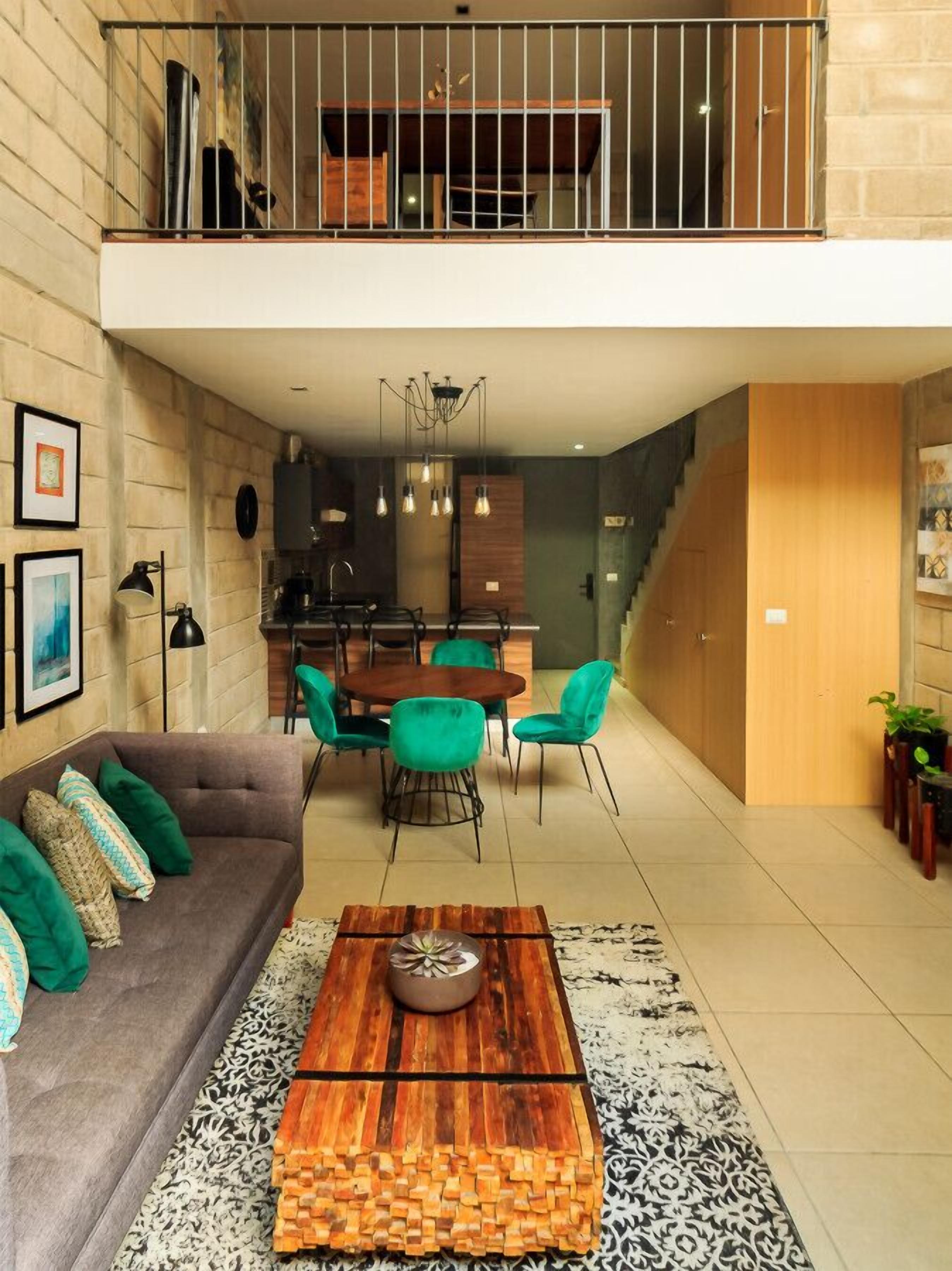 Una sala moderna con sofá, mesa de centro, comedor y escalera.