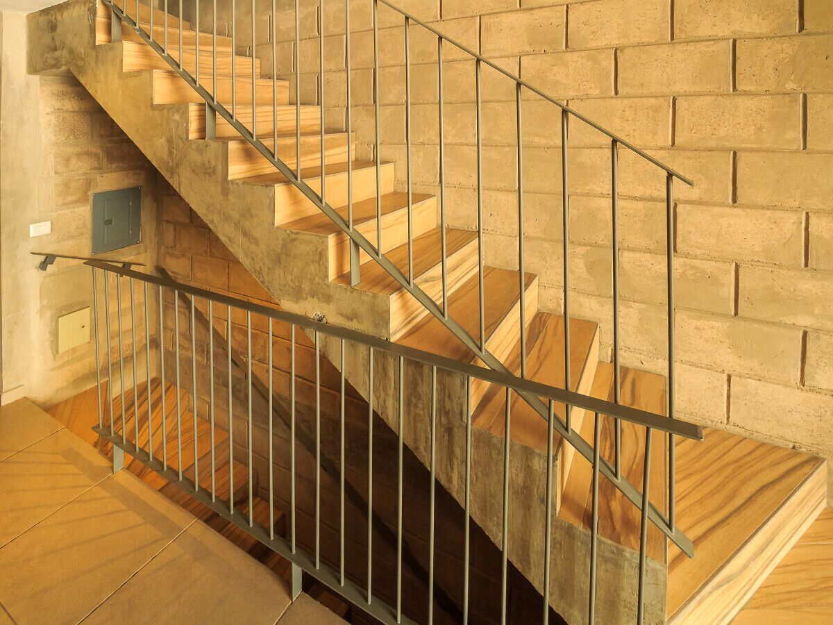 Una escalera de madera con barandillas de metal que baja a un nivel inferior.