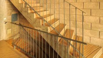 Una escalera de madera con barandillas de metal que baja a un nivel inferior.