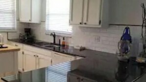 A modern kitchen with white cabinets, a black countertop, and a built-in island. - Beach Property with get away feeling. (Fort Myers Beach)