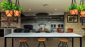 A bar area with a marble countertop, black metal stools, and hanging terracotta planters. - Inspiring Loft w/Gym & Coworking | 2 BD | Tribu Colón (Guadalajara)
