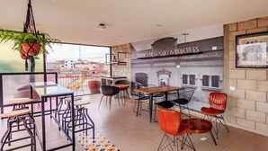 Ein modernes Café mit Wandgemälde, Außenplätzen und Blick auf die Stadt.