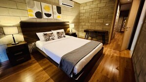 Ein Schlafzimmer mit einem Holzkopfteil, einem Bett mit weißer Bettwäsche, einem Nachttisch mit einer Lampe und einer wandmontierten Klimaanlage.