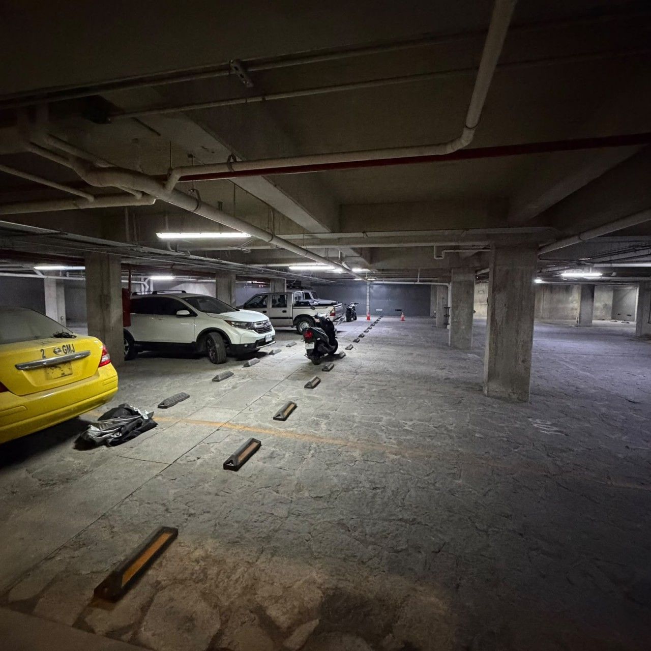 A multi-level parking garage with concrete pillars and overhead lighting.