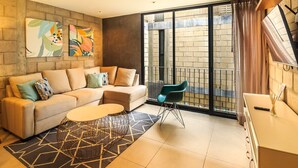 Una sala de estar moderna con un sofá, una mesa de centro y vistas a un edificio de ladrillo a través de amplios ventanales.
