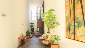 A spacious living area with a sofa set, a coffee table, and several potted plants.