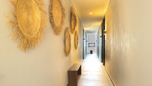 A hallway with a bench, decorative wall art, and a light fixture.