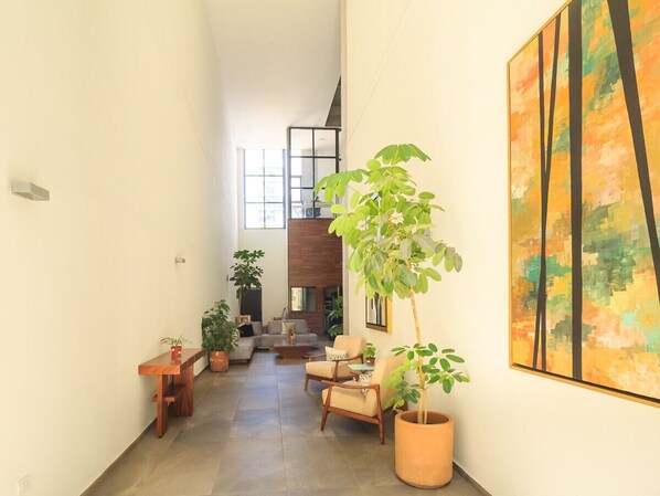 Un vaste espace de vie comprenant un ensemble de canapés, une table basse et plusieurs plantes en pot.