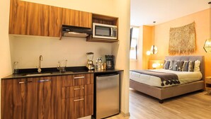 Une cuisine de taille réduite, dotée de meubles en bois, d’un four à micro-ondes encastré et d’un réfrigérateur compact.